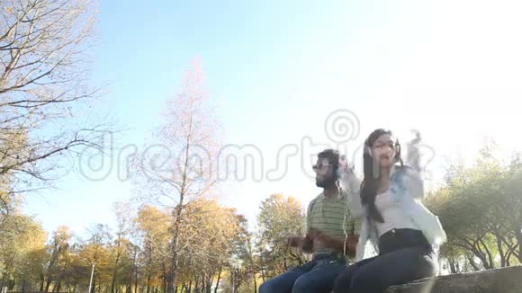 年轻夫妇在公园里用耳机听音乐玩得很开心视频的预览图