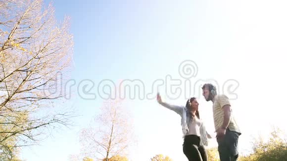 一对情侣听着耳机里的音乐在公园跳舞视频的预览图