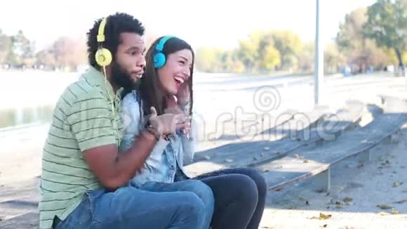 一对情侣在公园里用耳机听音乐视频的预览图