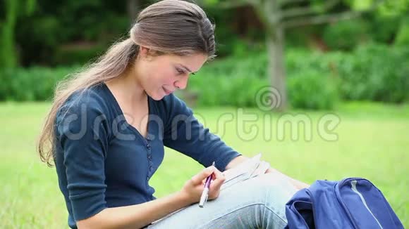 微笑的女人在笔记本上写字视频的预览图