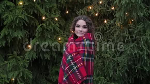 在圣诞树背景和花环的格子里的年轻女子视频的预览图