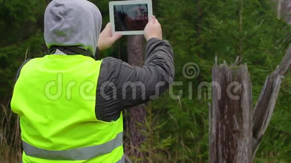在森林里用平板电脑拍摄的人视频的预览图