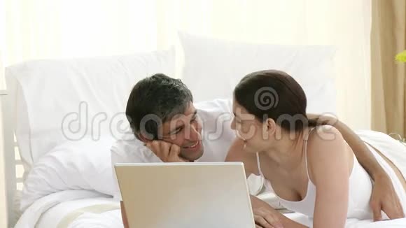 夫妻俩在床上用笔记本电脑视频的预览图