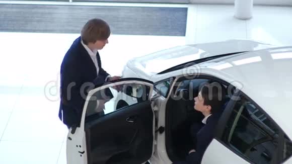 年轻顾客在汽车经销店检查汽车视频的预览图