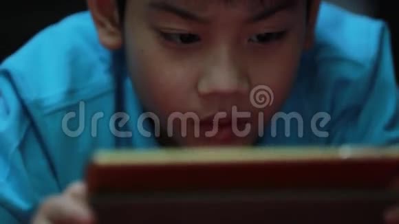 小亚裔男孩玩平板电脑游戏视频的预览图