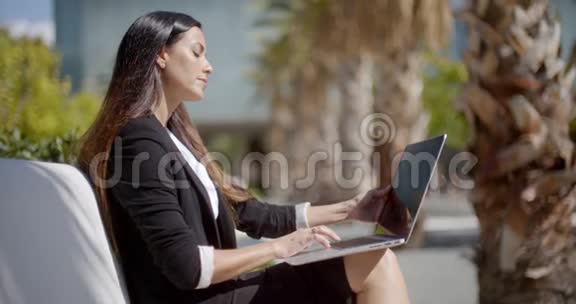 女商人坐在城市公园里工作视频的预览图