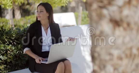 在公园里用笔记本电脑工作的女商人视频的预览图