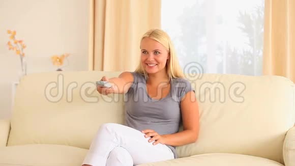 坐在沙发上的女人带着遥控器视频的预览图
