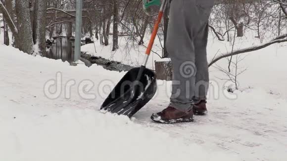 手里拿着雪铲的看门人从雪地上清理人行道视频的预览图