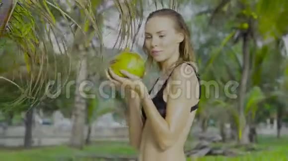 在美丽的夏日棕榈树间穿着黑色泳装的性感女人视频的预览图