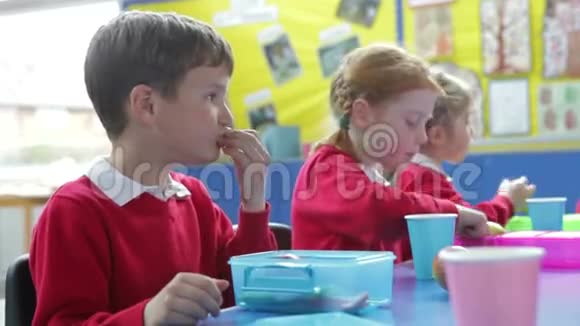 坐在桌旁的学童吃着盒饭视频的预览图