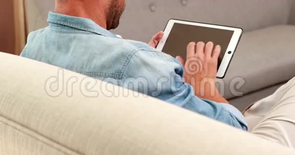 沙发上的帅哥用平板电脑视频的预览图