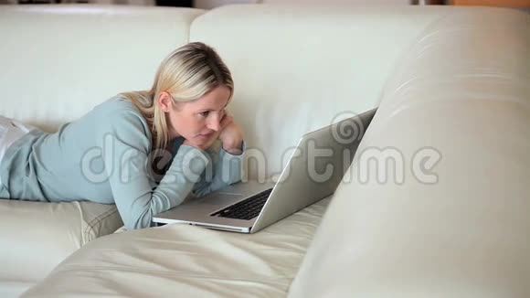 在沙发上看笔记本电脑的女人视频的预览图