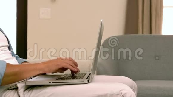 微笑的男人在沙发上用笔记本电脑视频的预览图