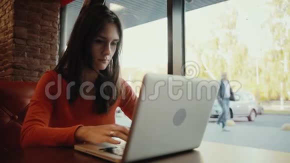 年轻女子在电脑上打字在咖啡馆里打电脑视频的预览图