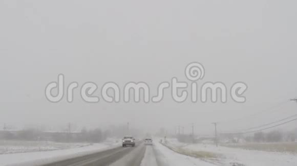在寒冷的冬季暴风雪中驾驶汽车行驶在道路上视频的预览图