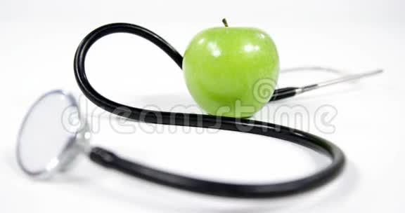 白色背景下的听诊器和苹果水果视频的预览图