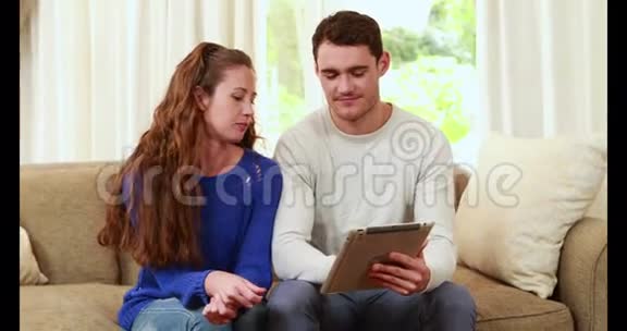 快乐的一对夫妇用笔记本电脑坐在沙发上视频的预览图