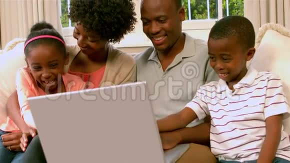 幸福的家庭在沙发上用笔记本电脑视频的预览图