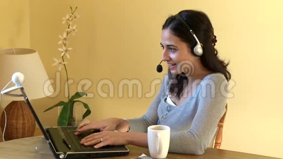 微笑的女人用耳机在网上聊天视频的预览图