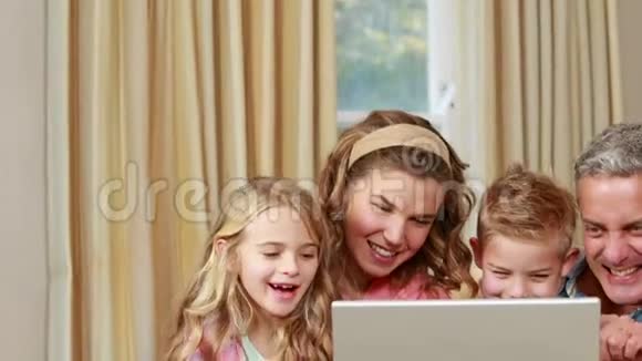 幸福的家庭在沙发上用笔记本电脑视频的预览图