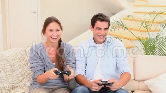 男人和女人坐在沙发上玩游戏机视频的预览图