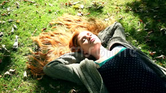 年轻的红头发在草坪上放松视频的预览图