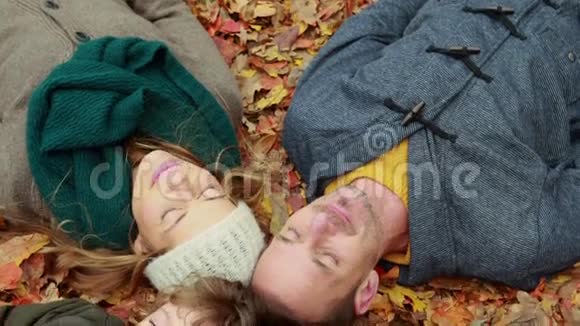 一家人躺在公园的秋叶上视频的预览图