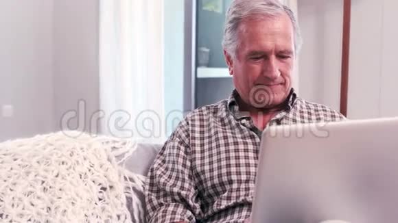 帅气的成熟男人在沙发上用笔记本电脑视频的预览图