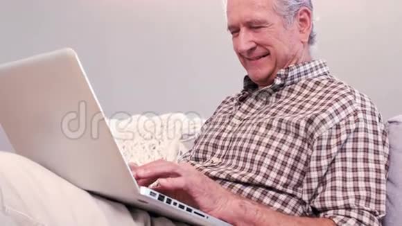 帅气的成熟男人在沙发上用笔记本电脑视频的预览图