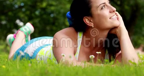 美丽的黑发女人躺在草地上视频的预览图