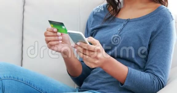 微笑的女人拿着手机和信用卡视频的预览图