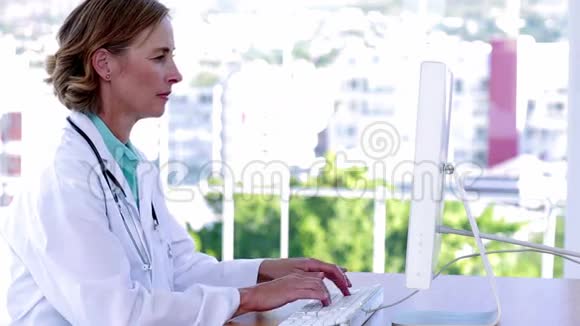 医生在她的办公桌前打字微笑着视频的预览图