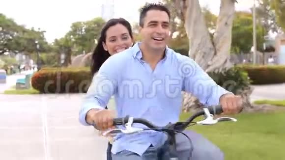年轻的西班牙夫妇骑自行车在公园里视频的预览图
