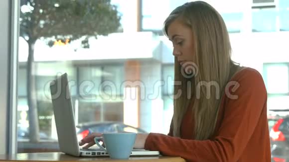 在咖啡馆里用笔记本电脑的金发美女视频的预览图