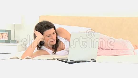 在床上拿着笔记本电脑的漂亮女人视频的预览图