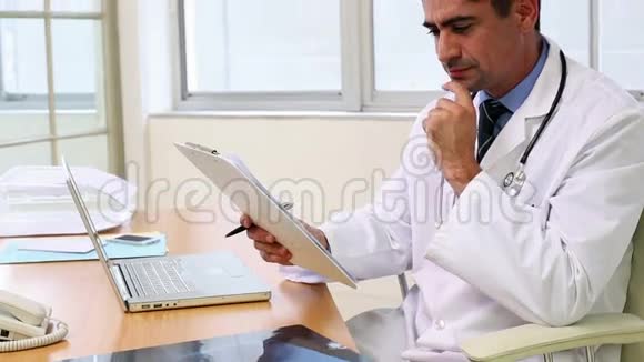 坐在桌子旁看文件的医生视频的预览图