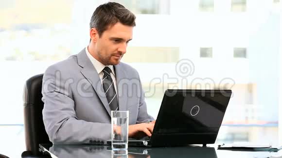 年轻的商人在他的笔记本电脑上工作视频的预览图