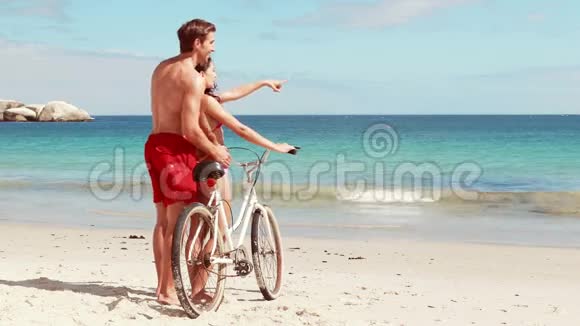 一对无忧无虑的夫妇在海滩上骑自行车视频的预览图