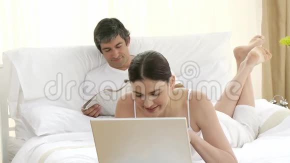 女人用笔记本电脑男人看报纸视频的预览图