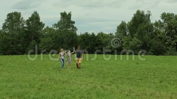 幸福的一家人走在绿色的草地上视频的预览图