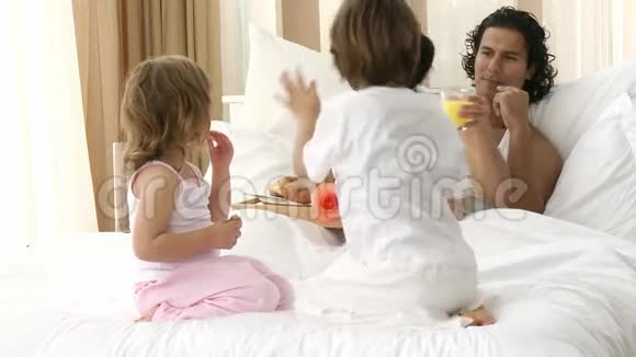 幸福的家庭在床上吃早餐视频的预览图