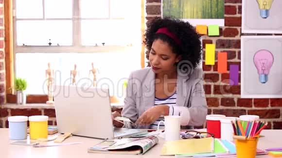 一位漂亮的设计师拿着笔记本电脑在办公桌上工作视频的预览图