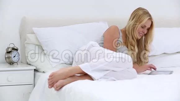 金发女人在床上用平板电脑视频的预览图