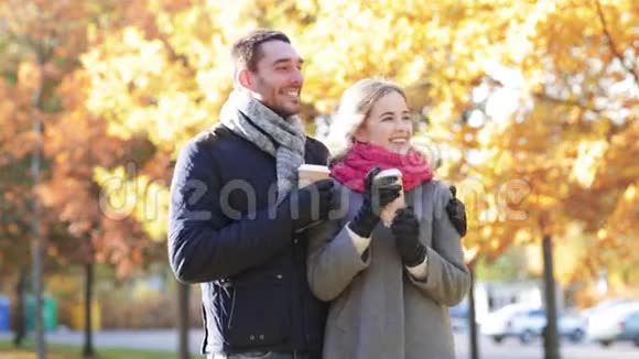 带着咖啡杯的微笑情侣在秋天公园视频的预览图