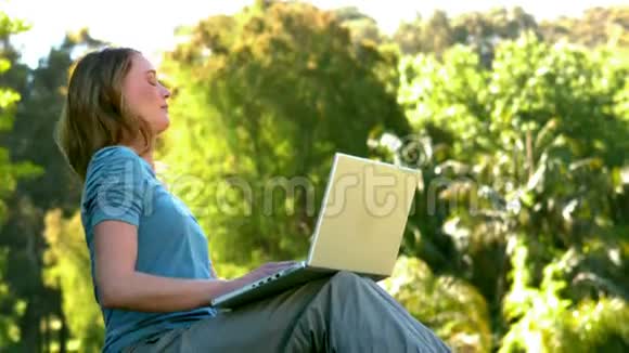 在公园里用笔记本电脑的年轻女子视频的预览图