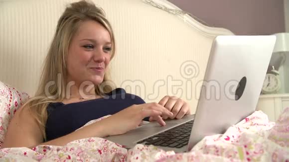 使用笔记本电脑躺在床上的少女视频的预览图