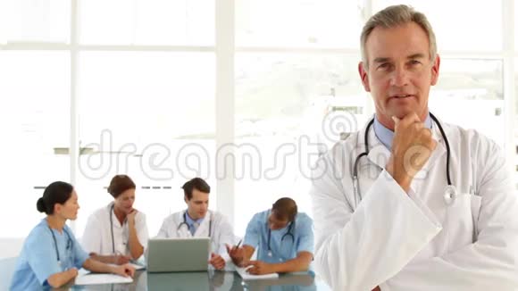 成熟的医生看工作人员和照相机视频的预览图