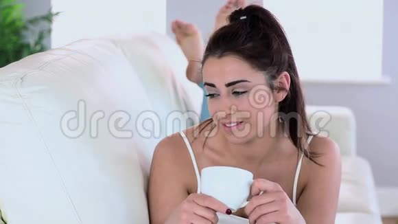 快乐的黑发女人在沙发上喝咖啡视频的预览图