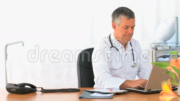 成熟的医生在他的笔记本电脑上工作视频的预览图
